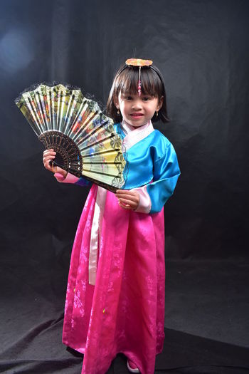 Cute girl in traditional clothing holding hand fan