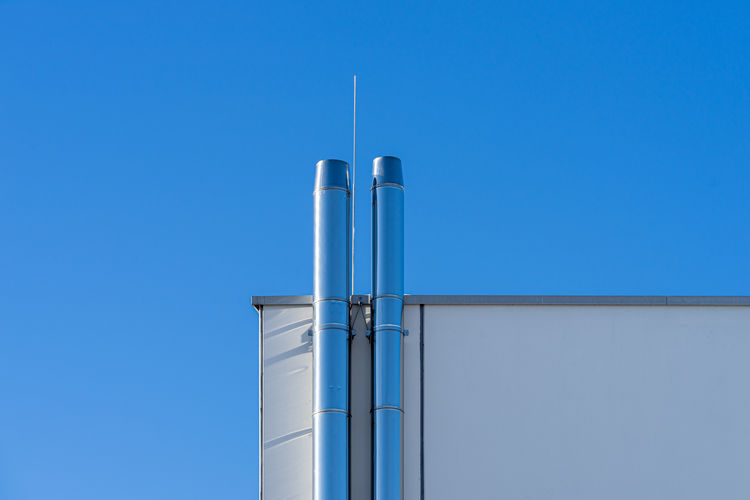 Low angle view of smoke stack against clear blue sky