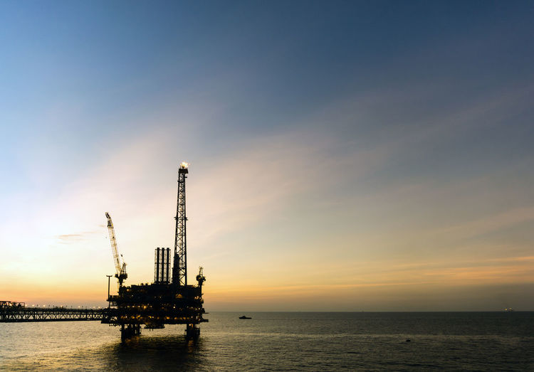 Silhouette of oil production platform during sunset at offshore oil field