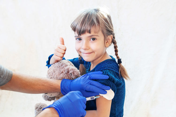 Hands giving vaccination to girl