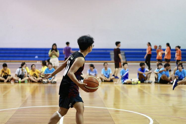 Young man with basketball in school gymnasium