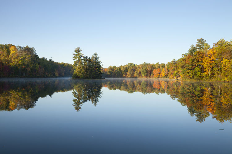 Beautiful lake with trees in autumn color and small island in northern minnesota on  a calm morning