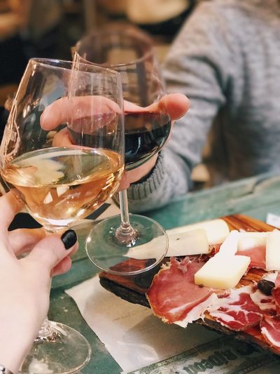 Cropped image of hand holding wine glass on table