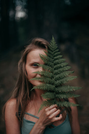 Portrait of young woman holding pine tree