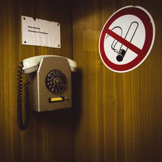 Pay phone by no smoking sign in telephone booth
