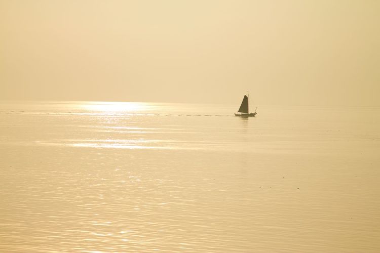 Sailboat in sea against sky during sunset