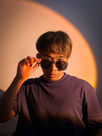 Portrait of boy with sunglasses against orange sky