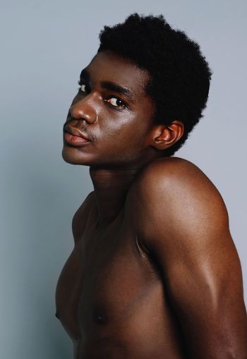 Portrait of shirtless young man against gray background
