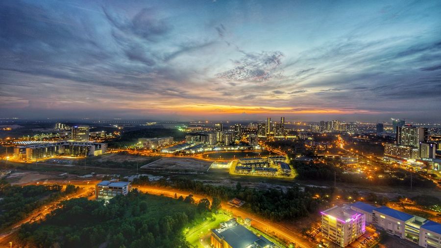 Aerial view of illuminated cityscape against sky at sunset