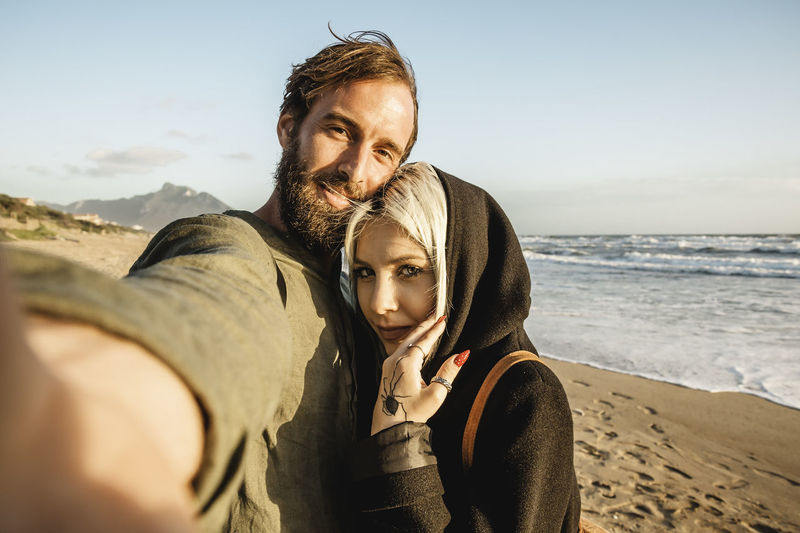 Portrait of couple on beach against sky