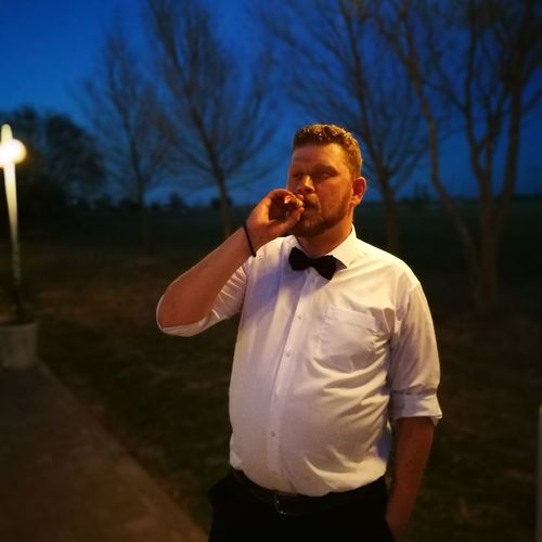 Man smoking while standing against bare trees