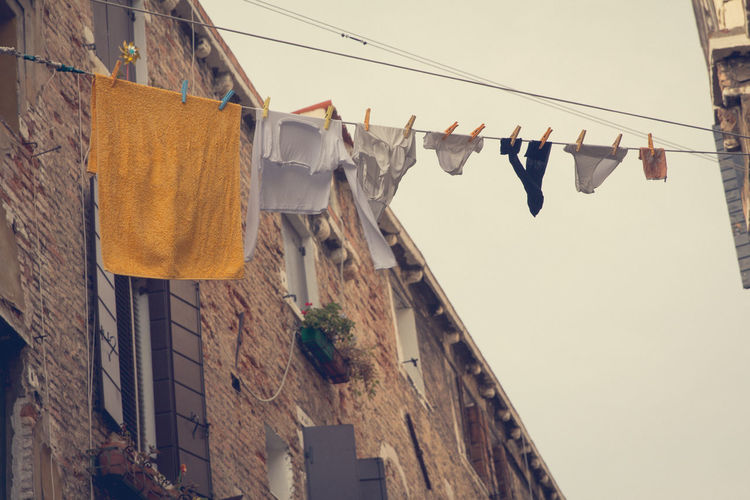 Low angle view of clothes hanging from string amidst buildings