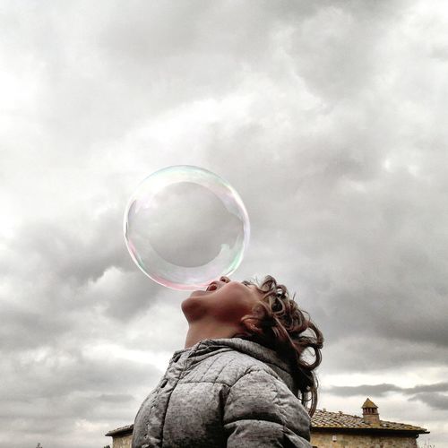 Low angle view of bubbles in mid-air against sky