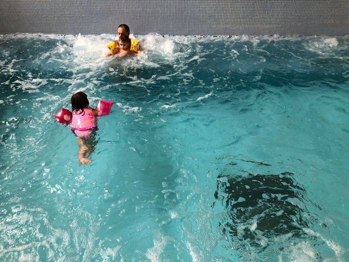 High angle view of father with children enjoying in swimming pool