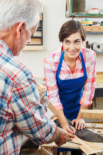 Smiling woman with man working in workshop