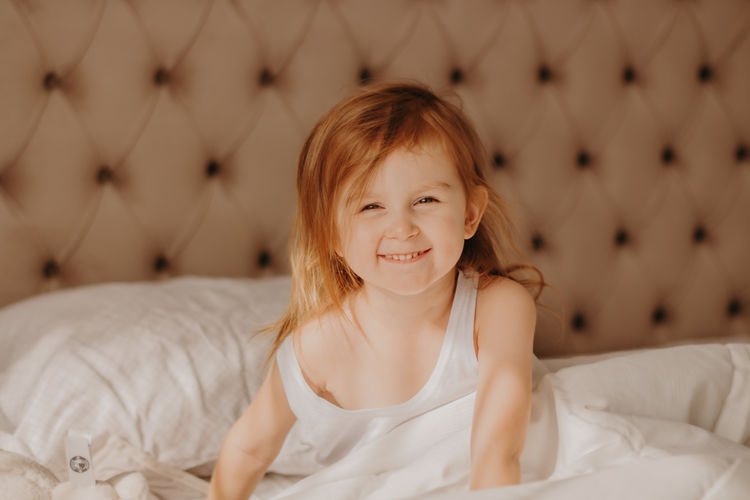 Portrait of cute little girl enjoying early morning on bed at home