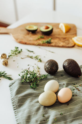 Ingredients for a meal: avocado, eggs, aromatic herbs on a table