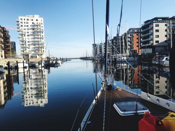Sailboats moored at harbor against buildings in city