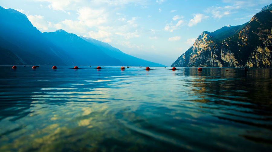 Close-up of lake garda with red buoys and mountains as a backdrop in riva del garda, trento, italy