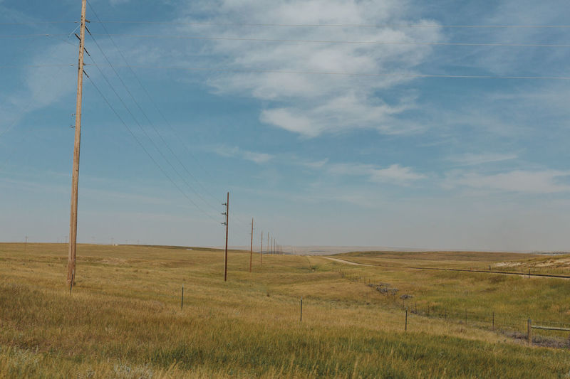 Scenic view of field against sky, power lines