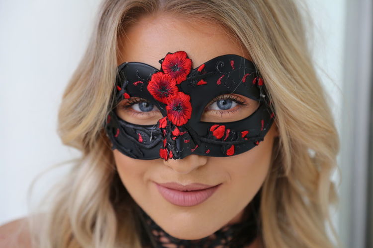 Portrait of a smiling young woman wearing sexy black and red mask