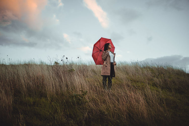 Young girl with a red umbrella in a field