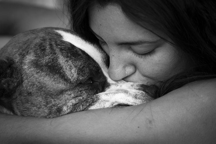 Close-up of woman kissing a dog sleeping