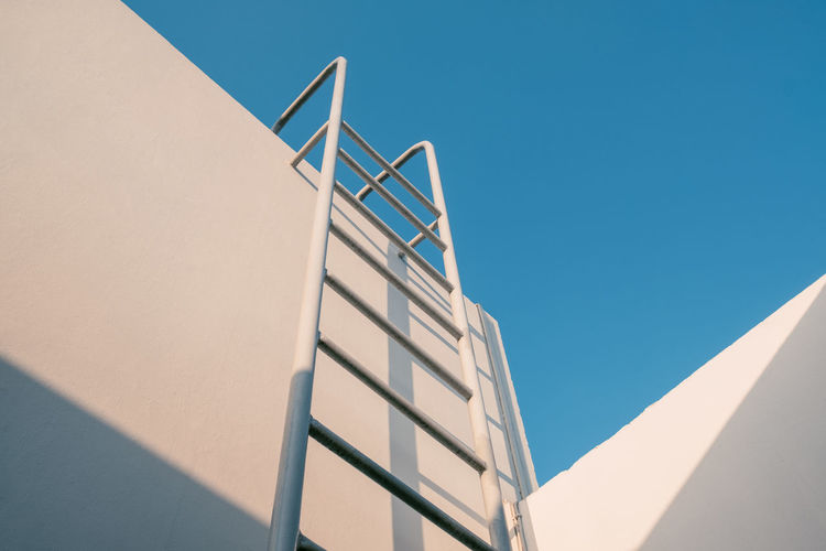 Low angle view of ladder on building against clear sky
