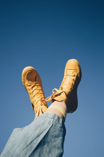 LOW SECTION OF MAN WEARING SHOES AGAINST CLEAR BLUE SKY