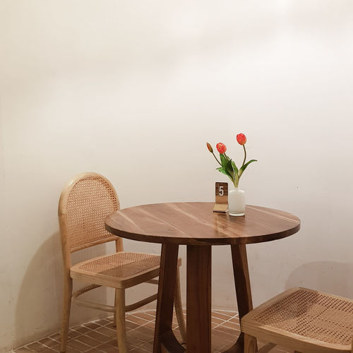 Red flower vase on table against wall
