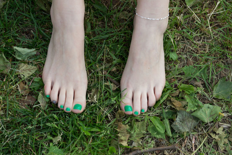Low section of woman with painted toenails on field