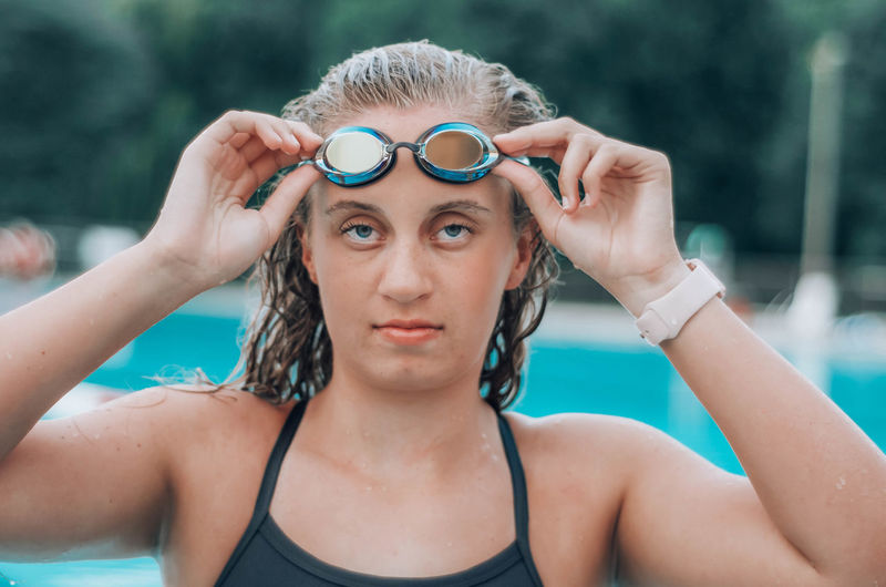Portrait of teenage girl wearing swimming glasses in swimming pool 