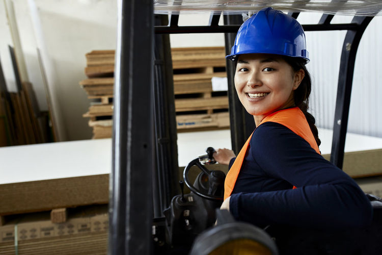 Portrait of confident female worker on forklift in factory