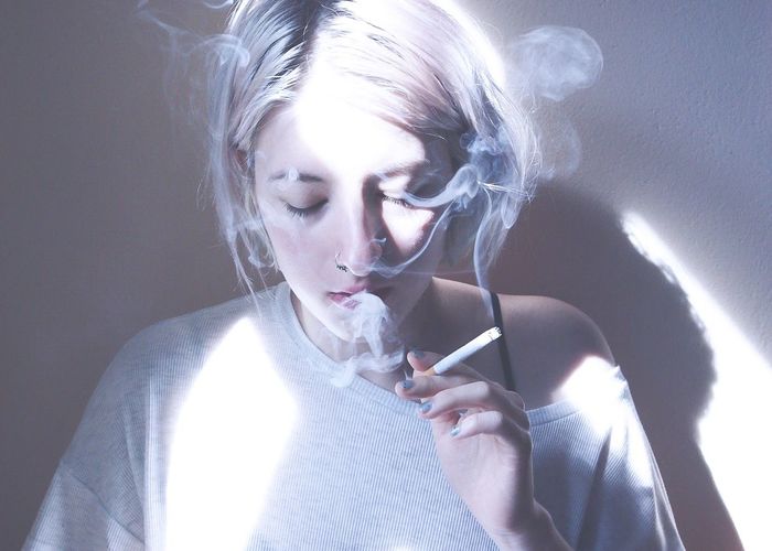 Young woman smoking against sky
