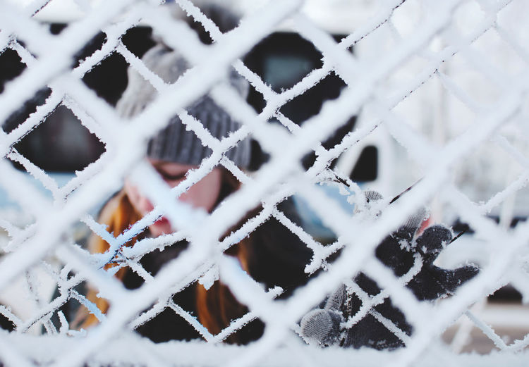 Woman seen through frozen fence