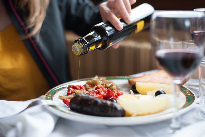 Midsection of woman pouring sauce in food