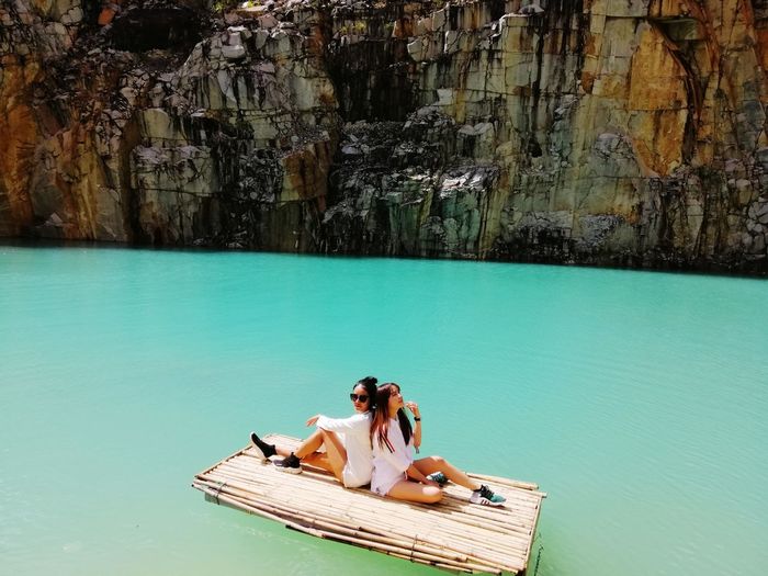 Full length of female friends siting on wooden raft