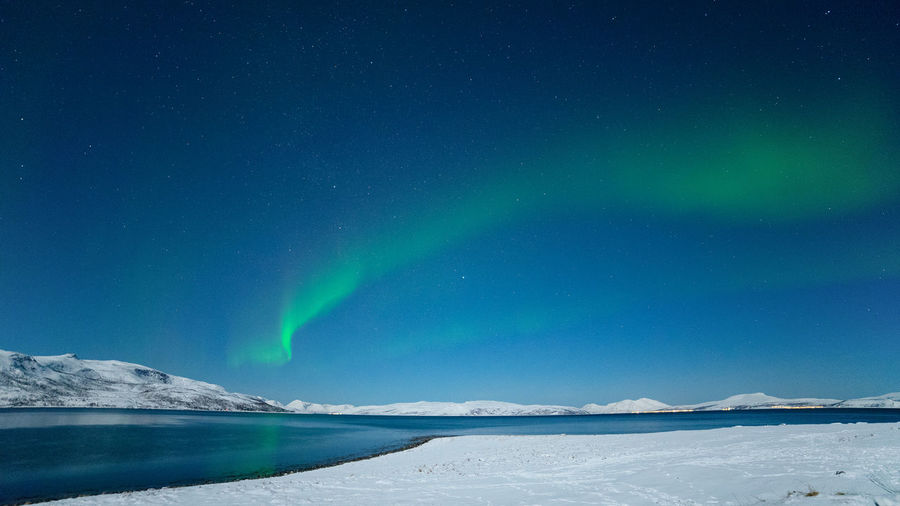Aurora borealis over lake against sky