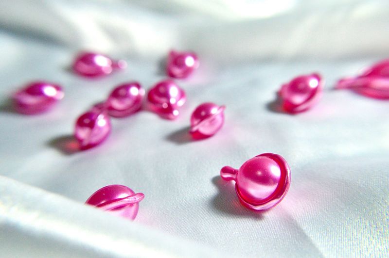 Close-up of pink vitamins capsules on white textile