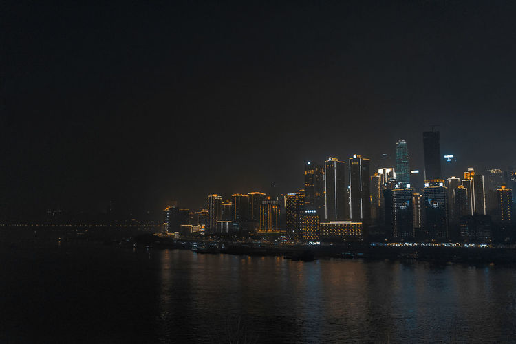 Illuminated buildings in city against sky at night