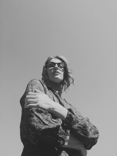 Low angle portrait of woman standing against clear sky