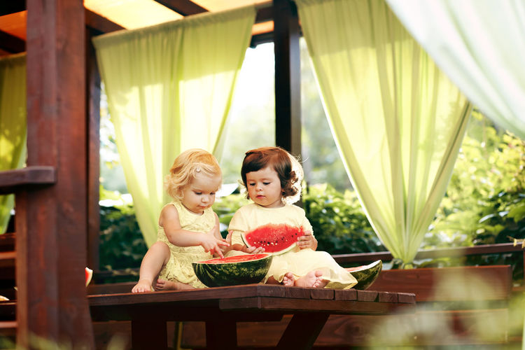 Girls eating watermelon on table