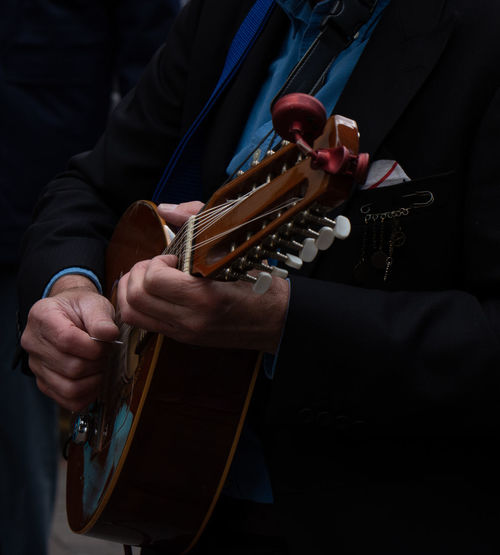 Midsection of man playing mandolin against black background
