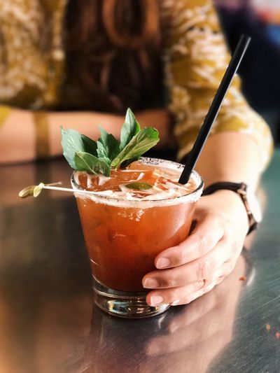 Midsection of woman with bloody mary on table