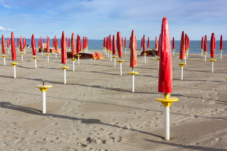 Row of wooden posts on beach against sky