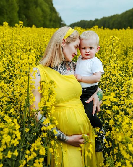 Pregnant woman with daughter standing by plants
