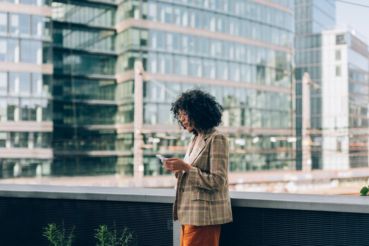 Fashion brazilian lady using mobile phone - trendy businesswoman under skyscrapers using phone