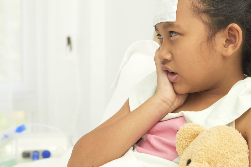 Close-up of girl with toothache in hospital