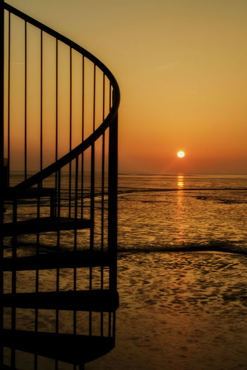 Silhouette steps on beach against clear sky during sunset