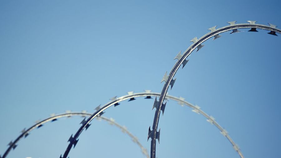 Low angle view of razor wire against clear sky
